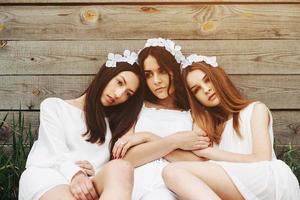 Three charming girls  near a wooden house photo