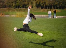 la chica deportiva saltando en el aire sobre la naturaleza demuestra un estiramiento perfecto. foto