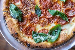 Pizza with sausage and basil, close view photo