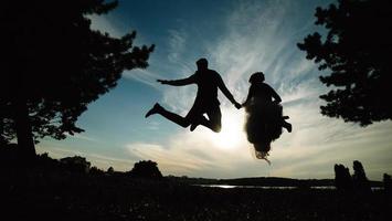 groom and bride jumping against the beautiful sky photo