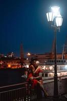 Guy and girl hugging each other on a background of the night port photo