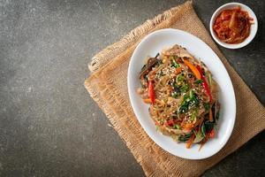 japchae or stir-fried Korean vermicelli noodles with vegetables and pork topped with white sesame photo