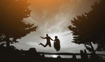 groom and bride jumping against the beautiful sky photo