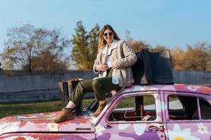 Young woman sits on an old decorated car photo
