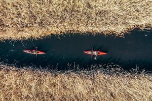 grupo de personas en kayaks entre juncos en el río de otoño. foto