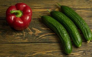 Fresh green cucumbers and sweet pepper isolated on wooden background