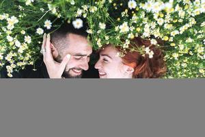 pareja joven se encuentra en el campo con margaritas. foto