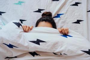 Closeup of Lovely young Woman Lies in Bed Covered with Blanket. photo