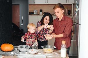 Dad, mom and little son cook a pie photo