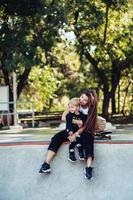 bella joven hipster mamá e hijo pequeño en el skatepark foto