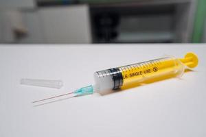 One one-off yellow medical syringe with needle lying photo