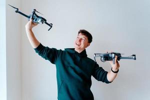 Guy holds two quadrocopters against a wall photo