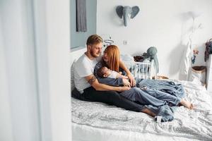 Happy family with newborn baby on the bed photo