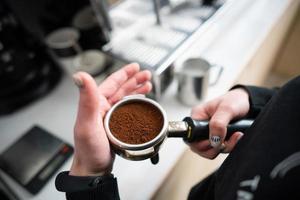 barista sosteniendo portafiltro con café molido foto