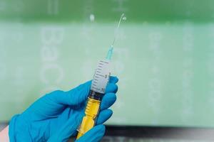 Hands in rubber gloves hold a disposable medical syringe with the drug photo