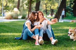 Two female friend sitting in the park have a rest take a selfie photo