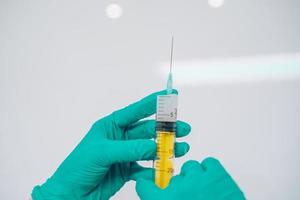 Hands in rubber gloves hold a disposable medical syringe with the drug photo