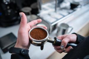 Barista holding portafilter with ground coffee photo