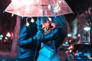 Guy and girl kissing under an umbrella photo