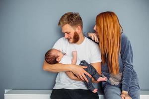 Young family with a baby by the wall photo