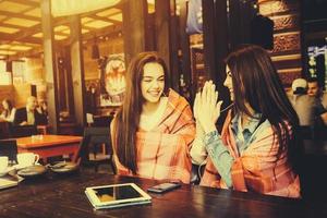 Two young and beautiful girls having fun in cafe photo