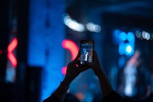 Person close up of recording video with smartphone during a concert. photo