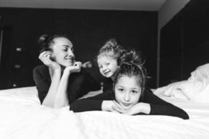 Mom and two daughters have fun on the bed photo