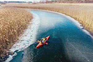 two athletic man floats on a red boat in river photo