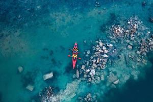 two athletic man floats on a red boat in river photo