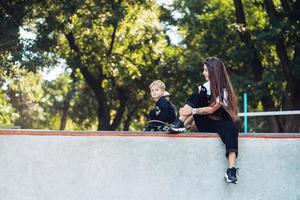 Beautiful young hipster mom and little son at the skatepark photo