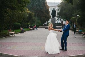 groom holds bride in his arms and twisted photo