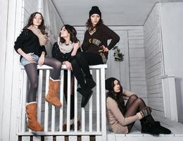 Four stylish models posing sitting on the fence. Christmas background photo