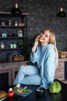 Beautiful girl talking on the mobile phone in kitchen at home photo