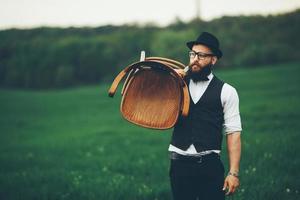 Bearded man carries a chair on the field photo