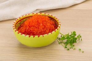 Red caviar in a bowl on wooden background photo