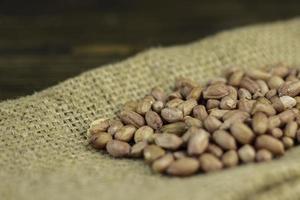 Raw peanuts on a rough cloth and wooden background photo