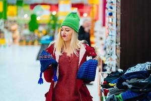 Young woman choosing hat in shopping center photo