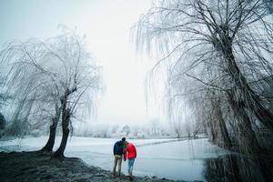 beautiful couple posing near a frozen river photo