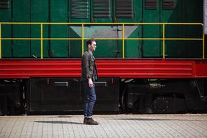 un hombre vestido con jeans en el fondo del tren y la estación foto