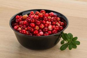 Cowberry in a bowl on wooden background photo