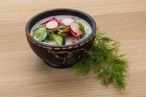 Okroshka in a bowl on wooden background photo