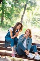 dos hermosas mujeres jóvenes descansando en un banco foto