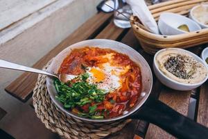 Shakshuka, Fried Eggs in Tomato Sauce on the Table photo