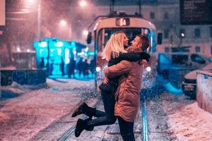 pareja de adultos jóvenes en la línea de tranvía cubierta de nieve foto