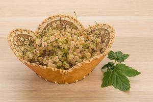 White currant in a basket on wooden background photo