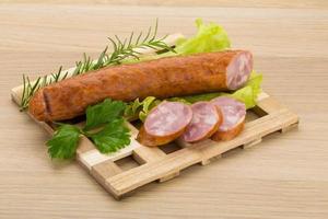 Sausage on wooden board and wooden background photo