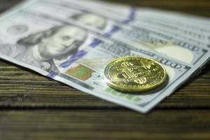 moneda de criptomoneda bitcoin y dólares en una superficie de madera foto