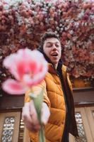 un hombre guapo tiene una flor, un tulipán rosa para su novia foto