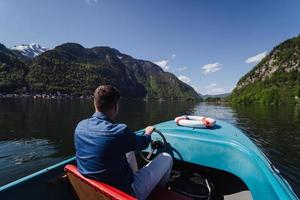 Handsome young guy controls a motorboat on a mountain lake photo