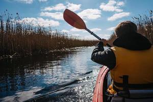 Group of people in kayaks among reeds on the autumn river. photo